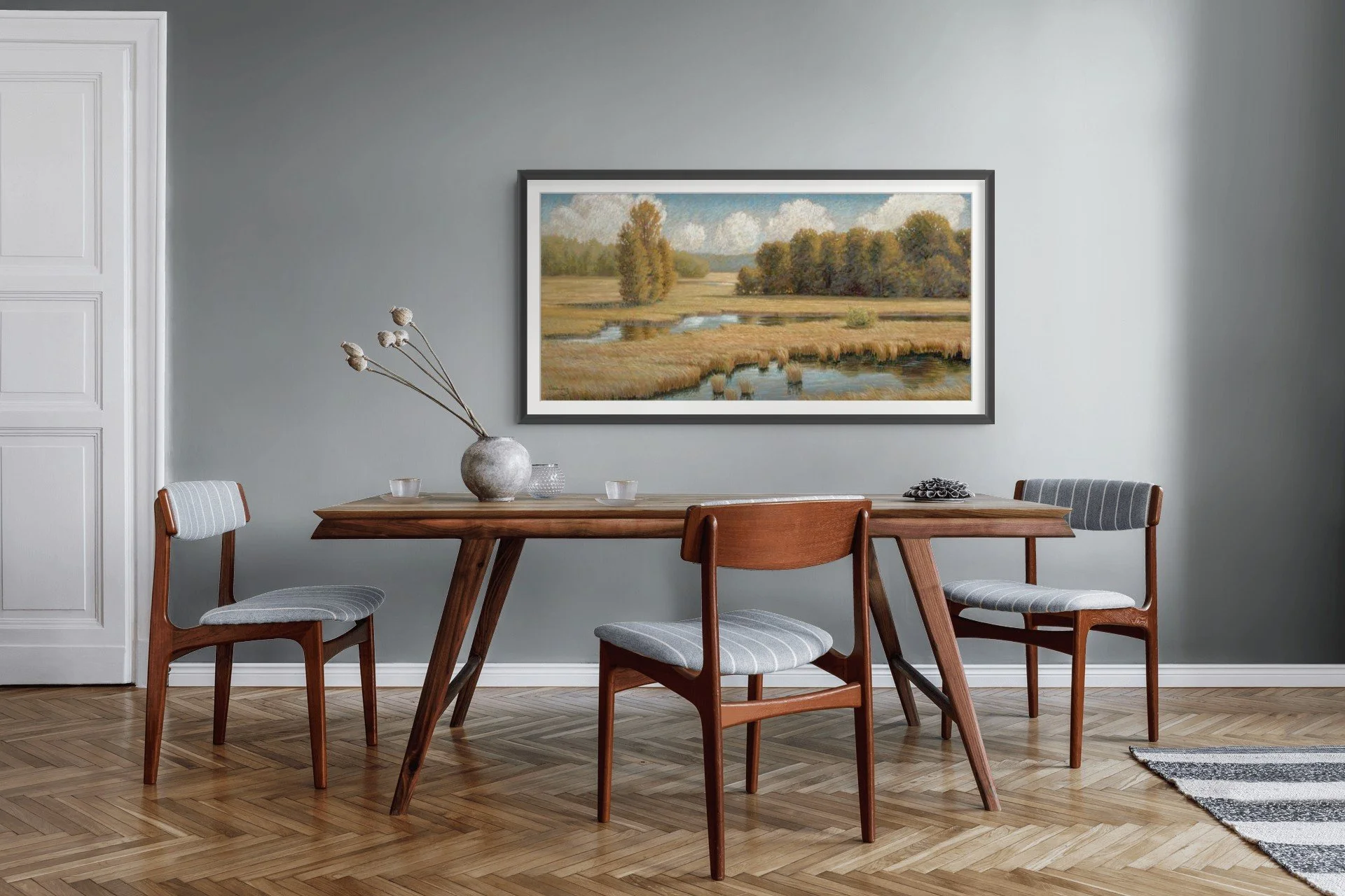 Horizontal prairie and wetland landscape painting displayed above a dining table in a contemporary interior