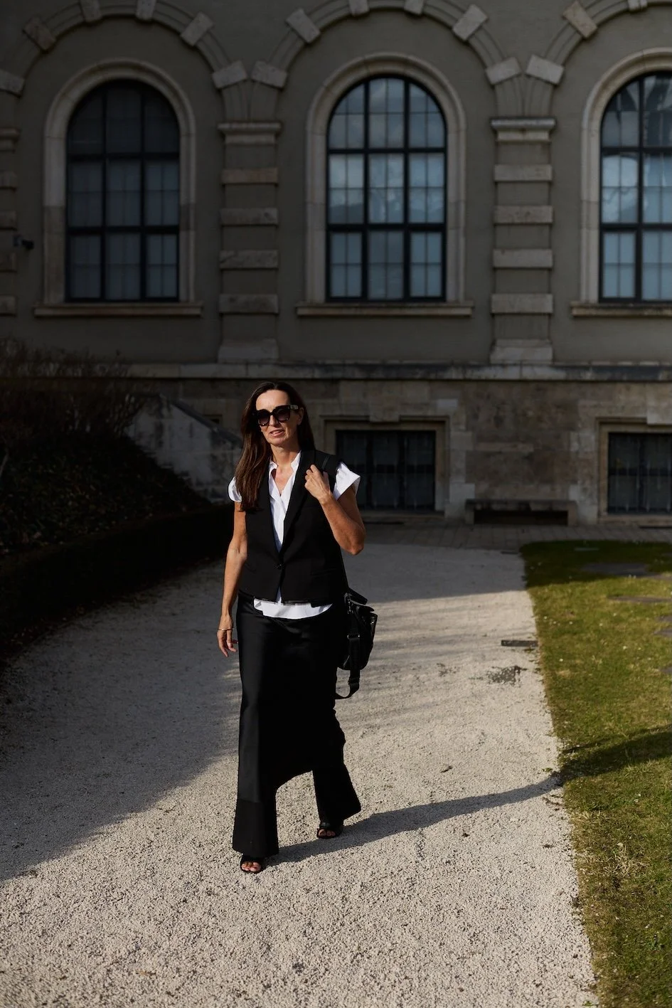 Dieser Look setzt neben dem Layering den Fokus ganz auf die Silhouette und die Materialien: fließend, dunkel und bewusst reduziert. Das Zusammenspiel aus Bootcut-Hose, Slip Dress und offenen Mules wirkt ruhig und selbstverständlich.