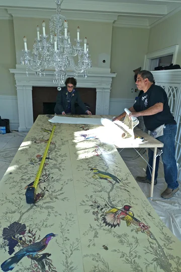 “Birds & Bees,” the wallpaper that the owner selected from the vendor Timorous Beasties, is rolled out for installation by Robert Montagnese of Wallpapers Unlimited, to enliven the formal Dining Room with full-size birds and bees.