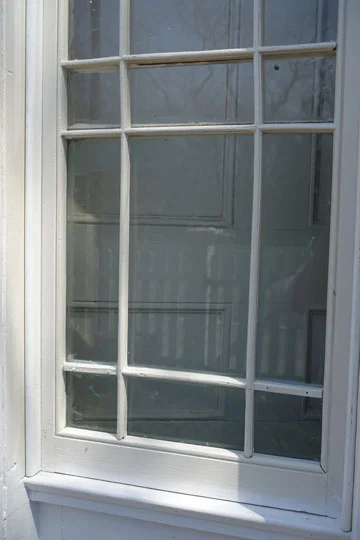 Detail showing the restoration of the original thin wood frame applied over the window glass on both sides at the front door sidelights.