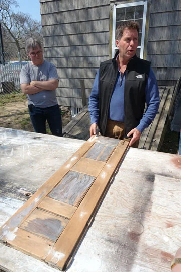 Jeremiah McGiff shows the group the shutter up close, where he has repaired damage and restored original material. Paint analysis shows the shutters were originally painted white, to match the trim.