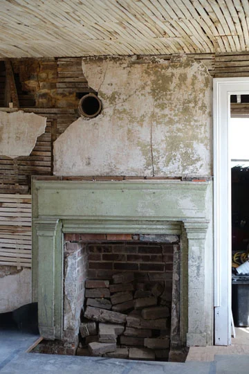 The fireplace is off center, and there is another room behind this, “the shed.”