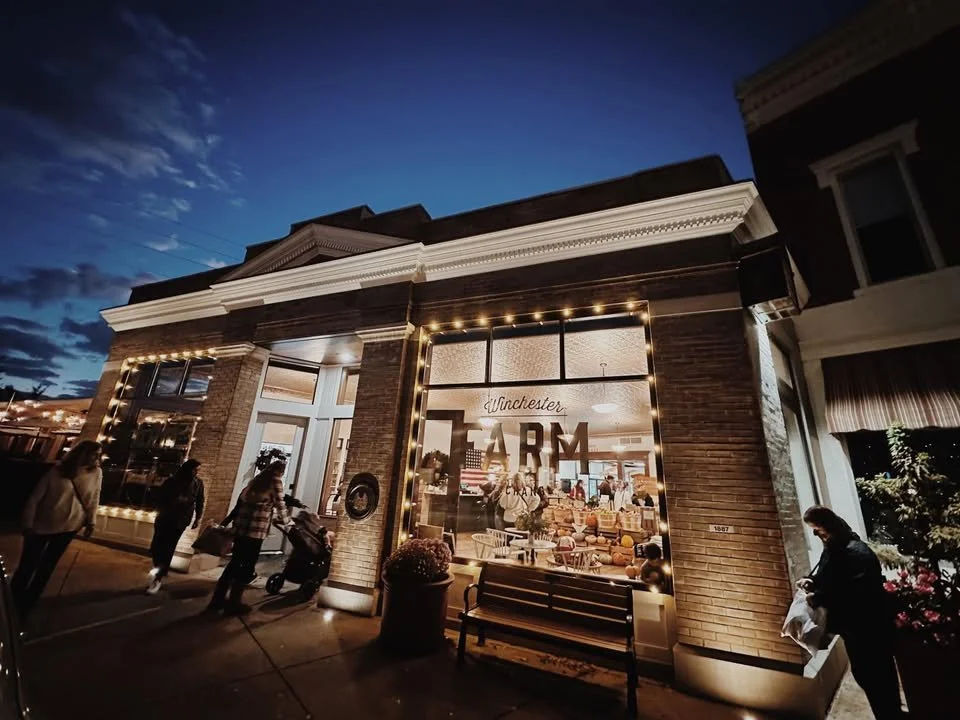 photo of the winchester farm exchange from the outside with the lights on and people shopping seen through the windows