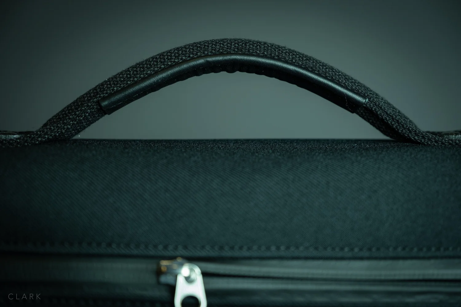 The handle is fairly rigid and easy to grab. It’s riveted and stitched to the top of the bag which has an internal support