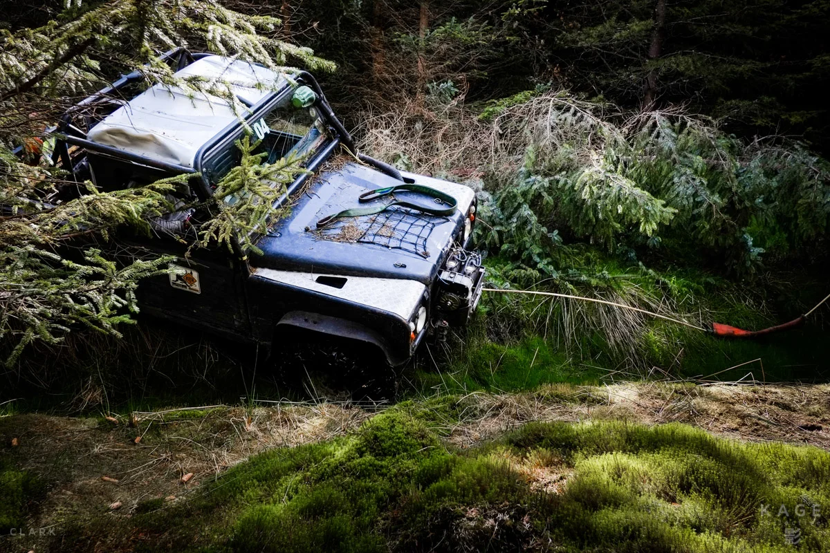 A driver waits patiently as his co-driver attaches their Land Rover’s winch to a tree in an attempt to pull them out of a ditch.