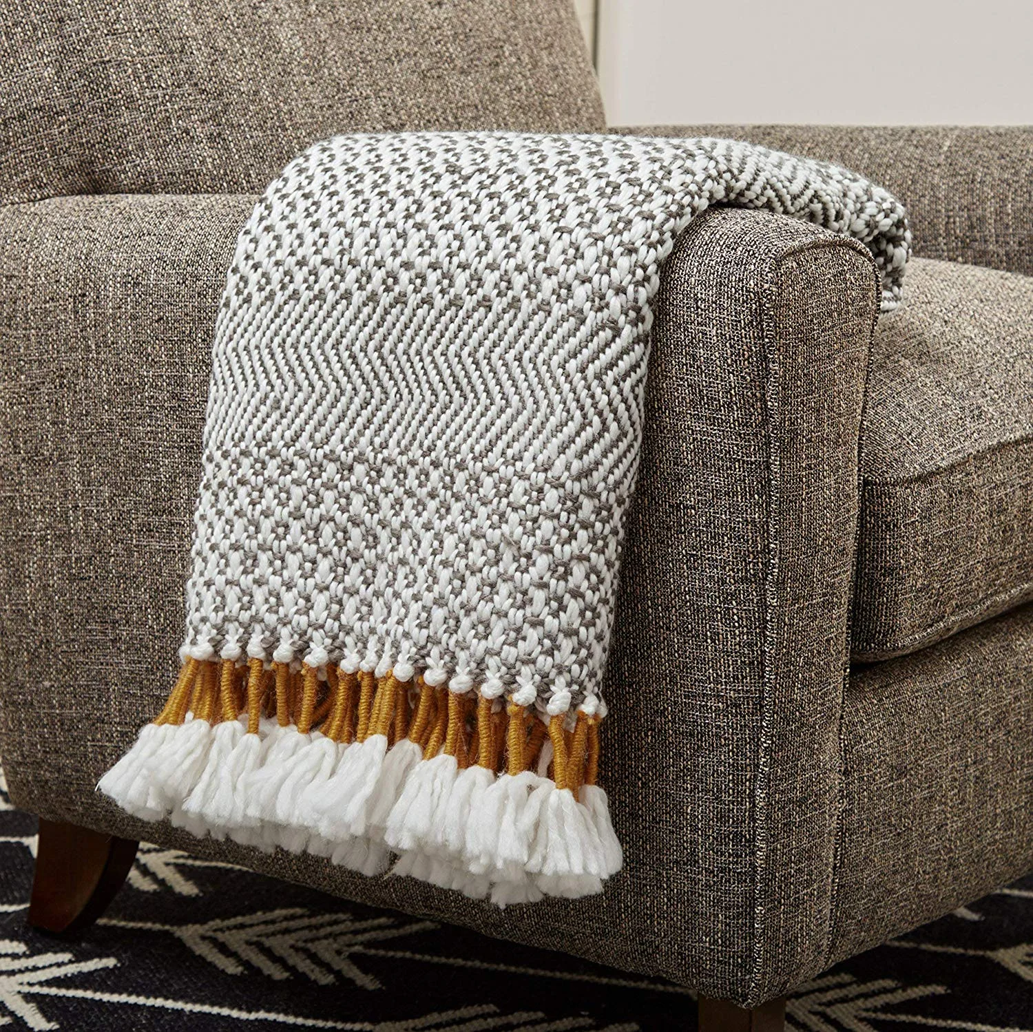 Hand woven throw blanket in shades of charcoal with mustard fringe.