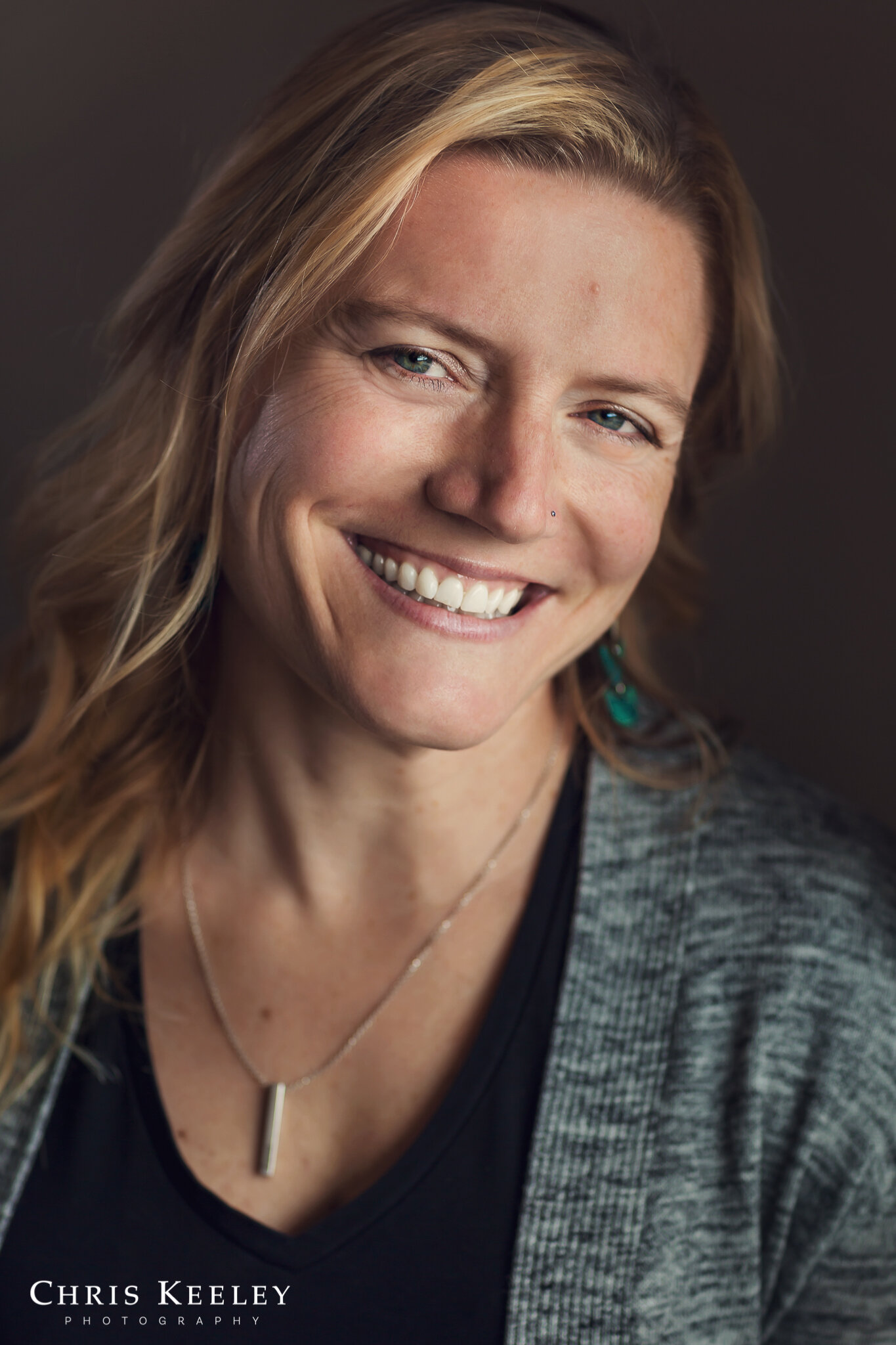 I love the layers in this headshot, the pendant necklace with black shirt and gray sweater just make it visually a little more interesting.