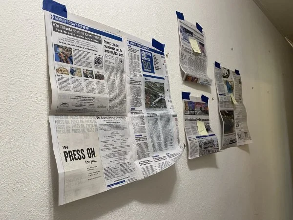 several pieces of newspaper taped to a wall as positions for works of art