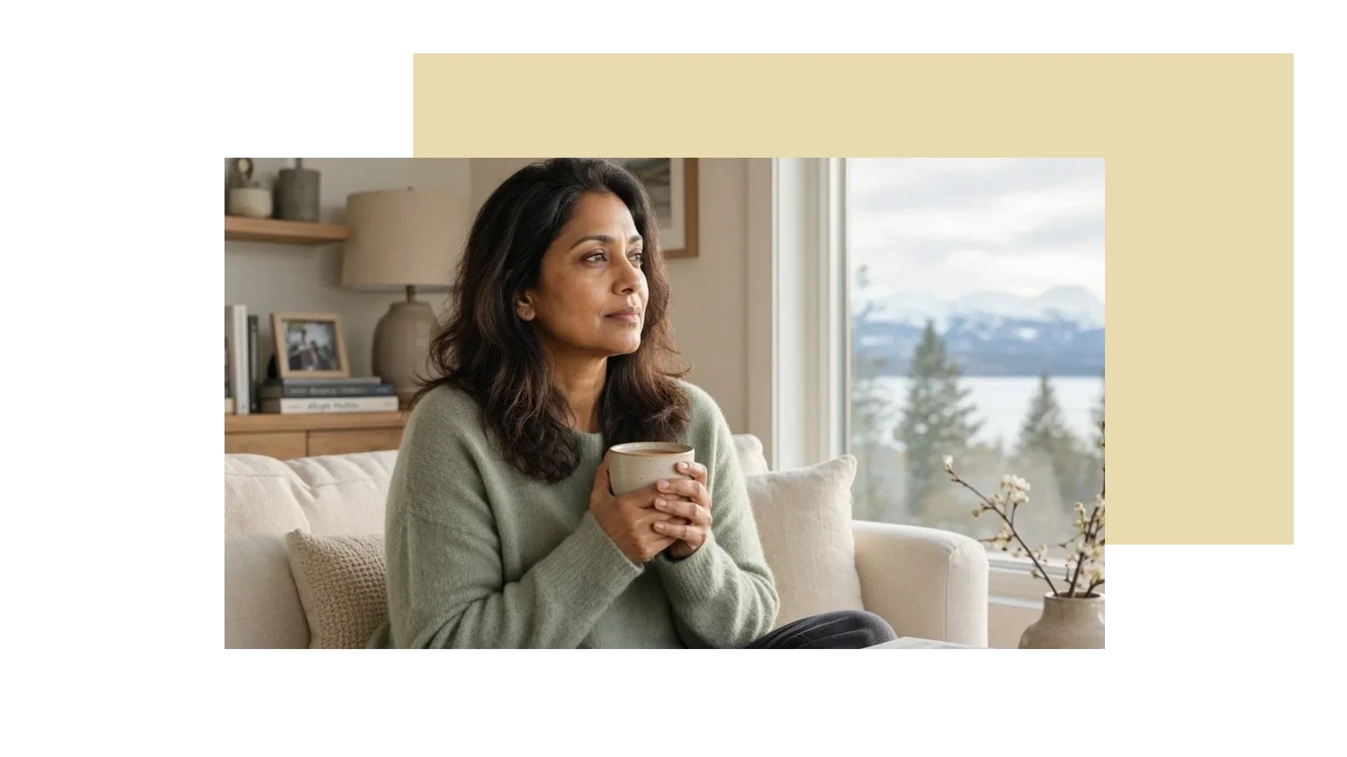 Woman holding a mug and looking out a window while thinking about a life transition