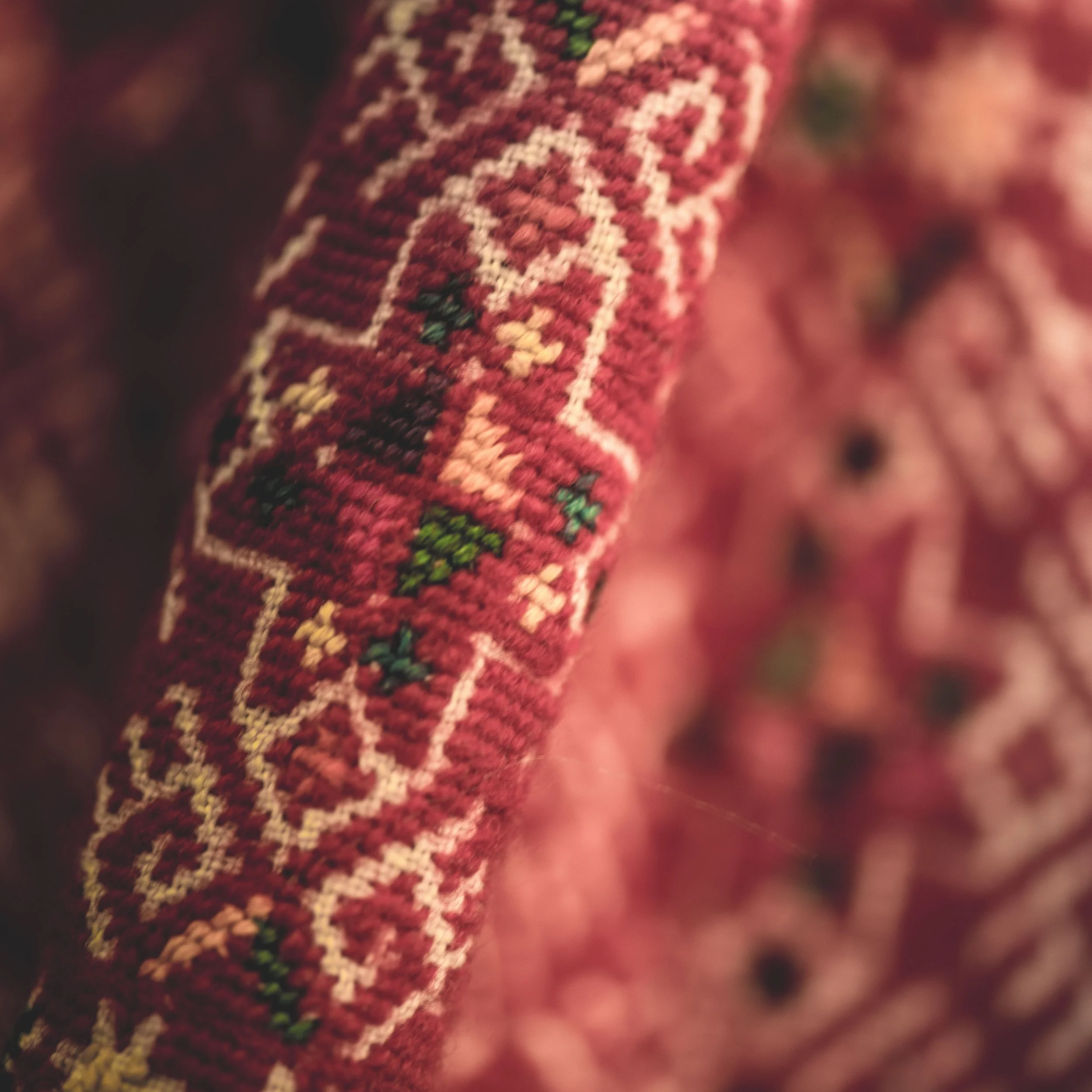 Close-up of a woven textile with a Christmas-themed pattern, featuring the words 'Merry Christmas' surrounded by small trees and decorative motifs in red, green, and white colors.
