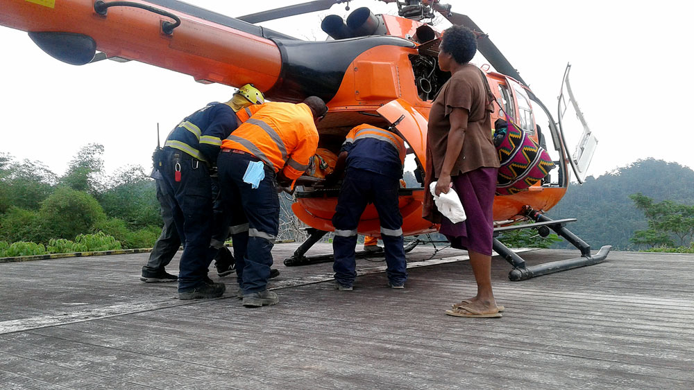 The Wafi-Golpu project team assisting with the medivac of Lupito to the Manolos Helicopter at the Wafi camp helipad.
