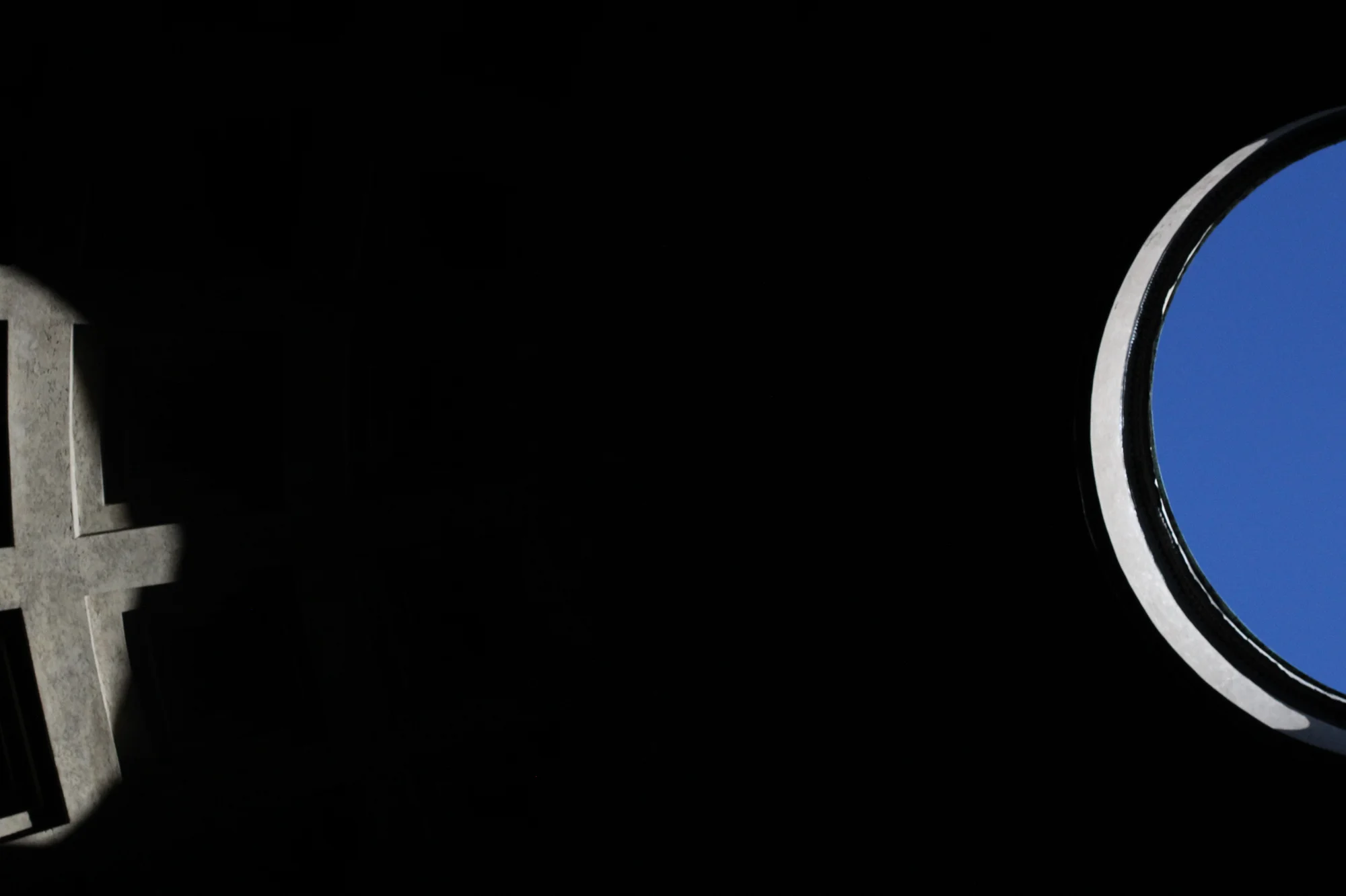 A telescope pointing toward the sky during the daytime, with a clear blue sky visible through its lens.