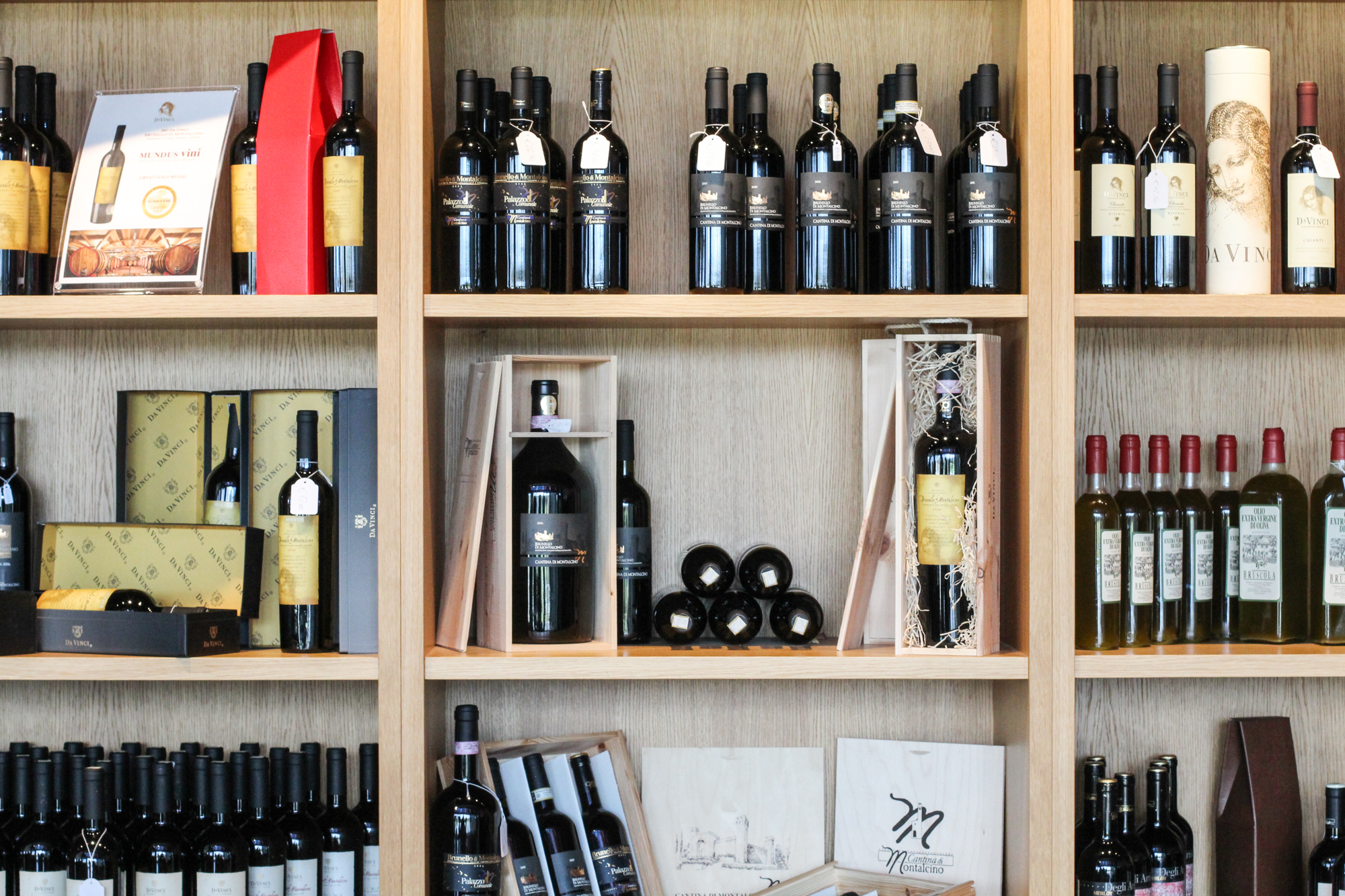 Wooden shelves filled with bottles of wine and various wine boxes and packaging.