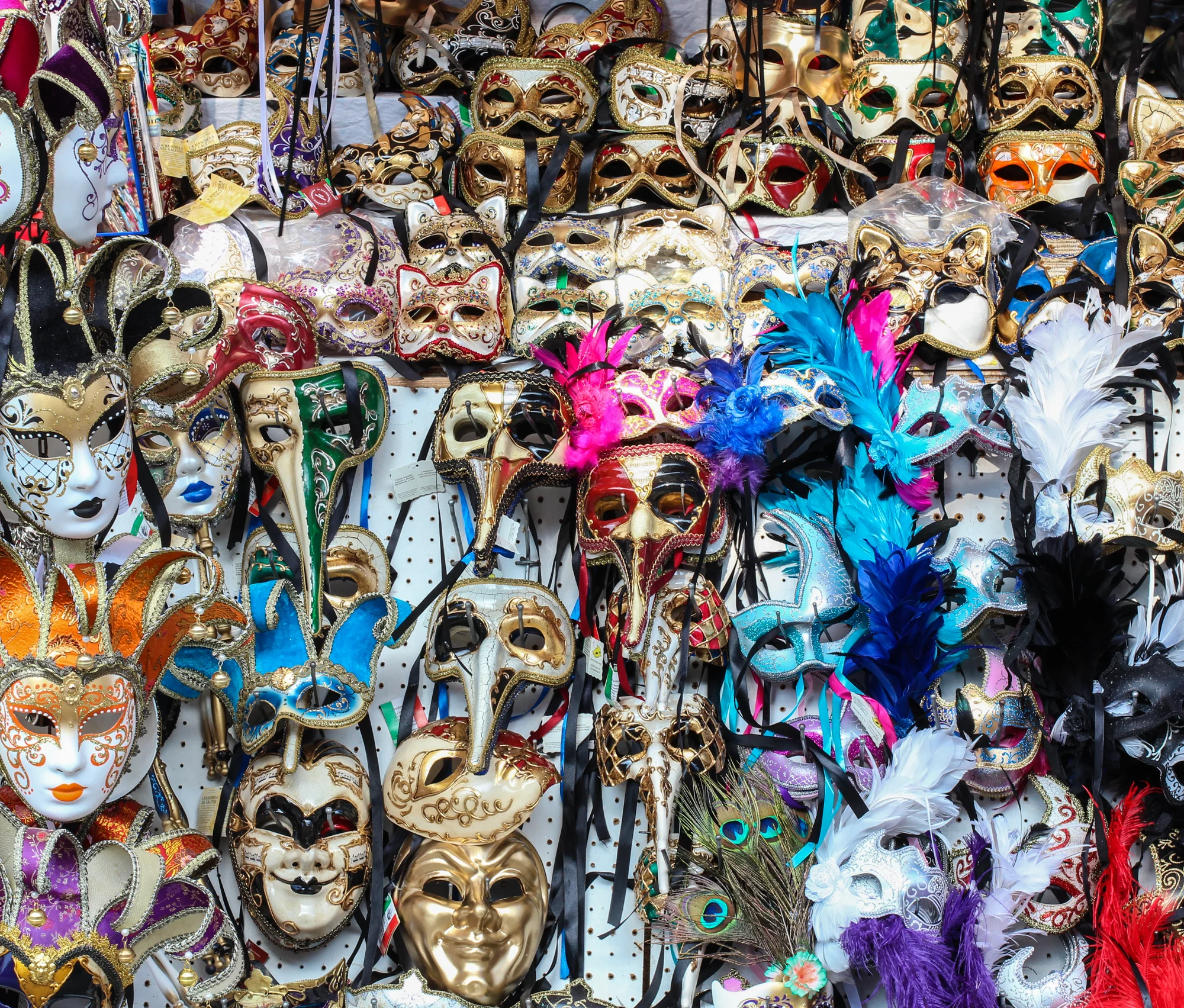 A display of colorful carnival masks with various elaborate designs, feathers, and embellishments.