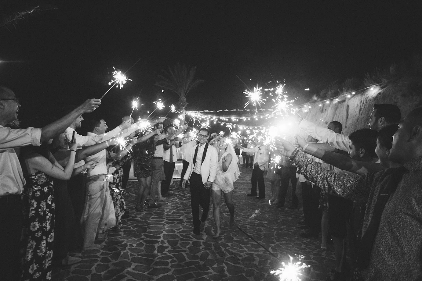 Bride and groom run through a sparkler exit at Pueblo Bonito Sunset Beach resort.