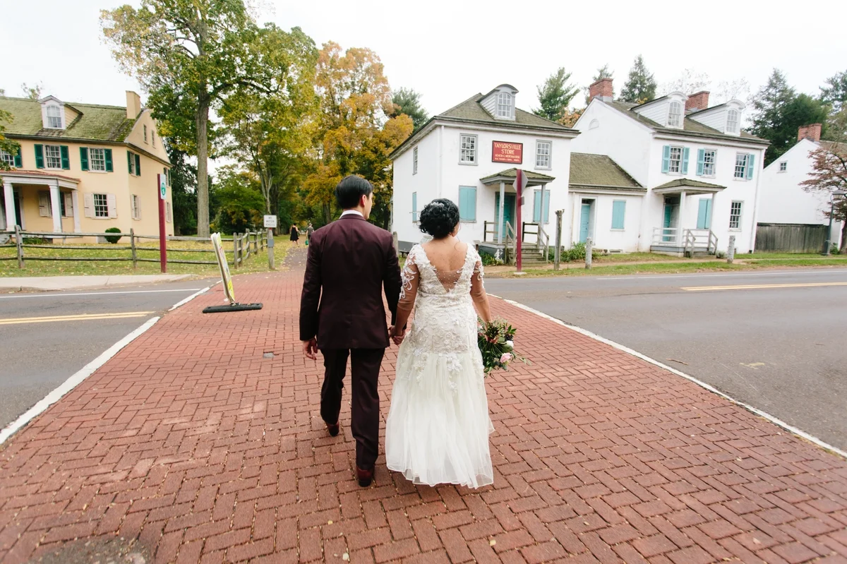 The groom and bride cross the street through the historic buildings at Washington Crossing Park.