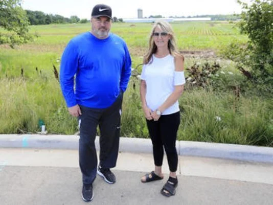Ledgeview residents Mike McCarthy and Charity Schneider stand at the end of a cul-de-sac in their neighborhood next to a farmland where construction of a manure pit is being proposed..