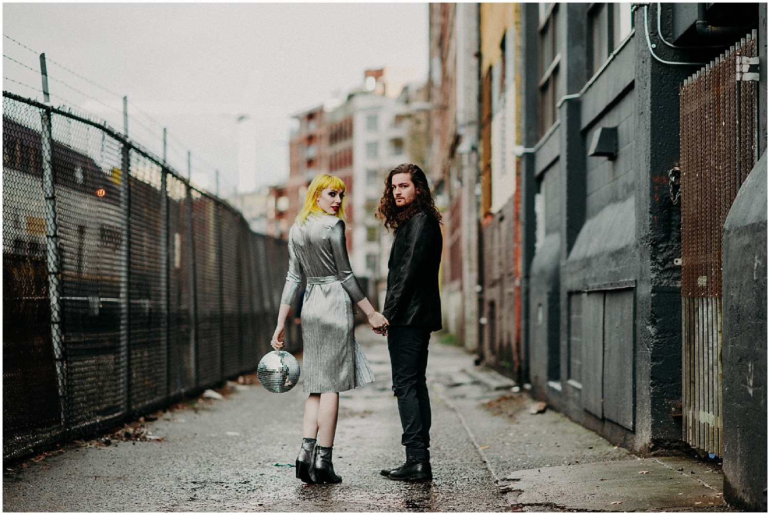  Vancouver back alley glamour grunge modern disco ball metallic dress shoes black suit curly long hair man engagement couples session concrete train chain link fence buildings 