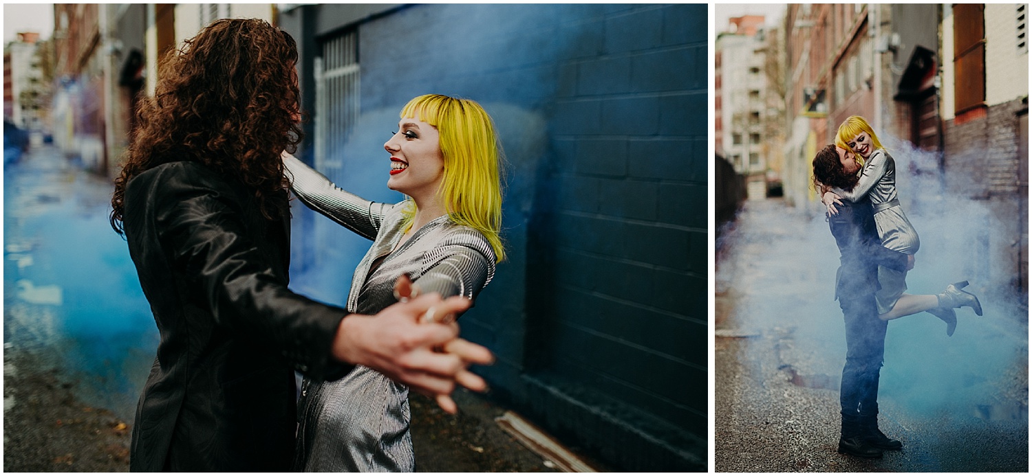  Vancouver glamour grunge back alley magic fog steam hand holding enchanting fun love smile yellow hair woman curly long locks man metallic dress style black brick wall forefront focus squeeze&nbsp; 