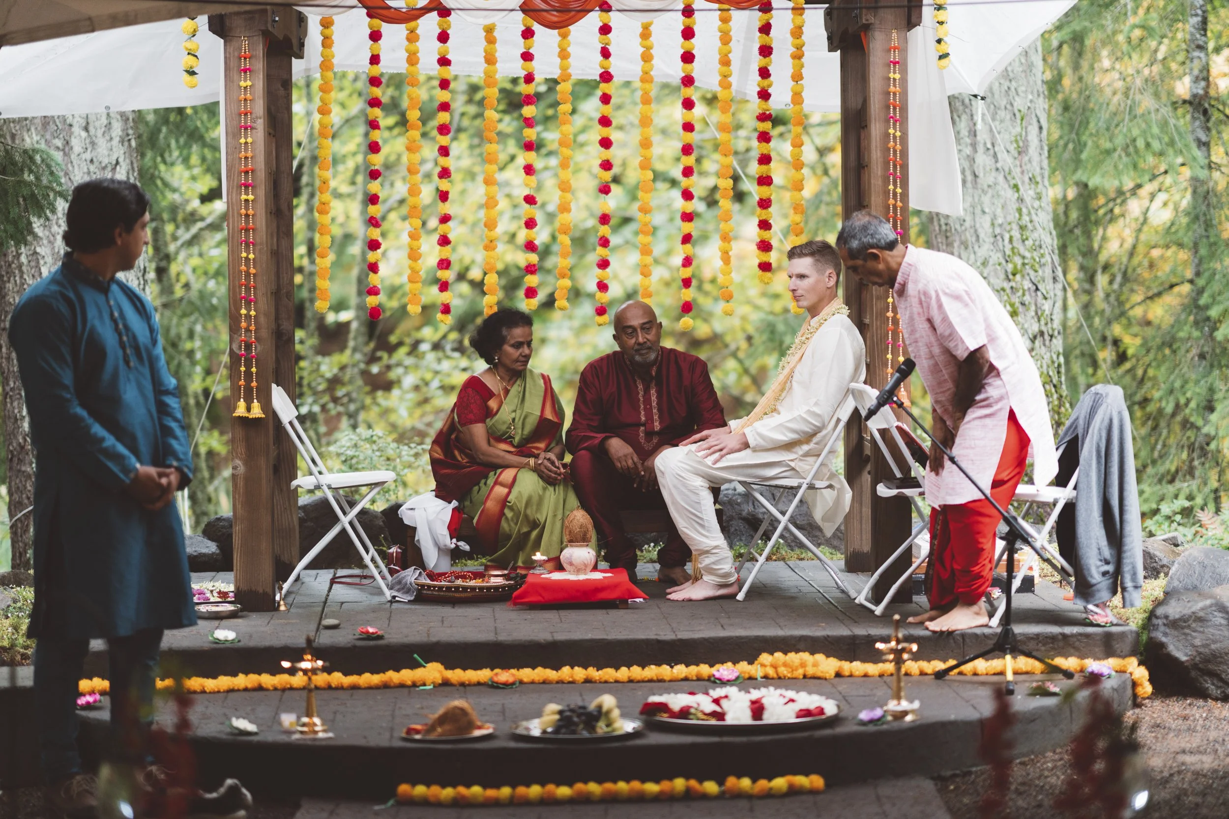 Hindu wedding ceremony outdoors with floral decorations and traditional attire.