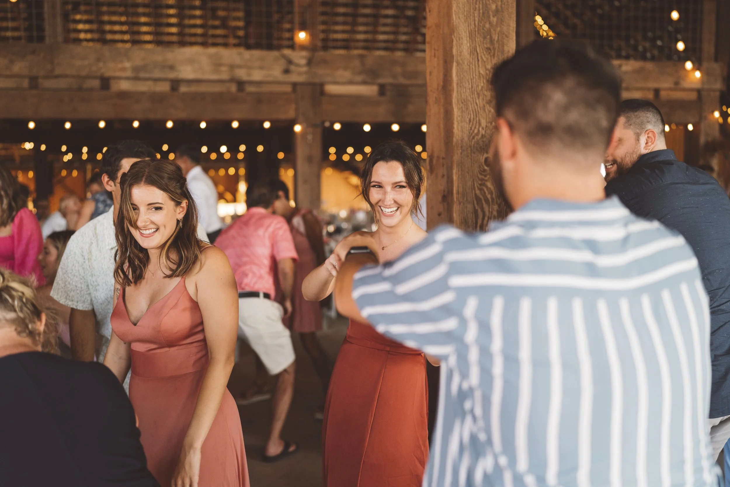Group of friends at a social gathering, smiling and enjoying conversation in a rustic, warmly lit setting.