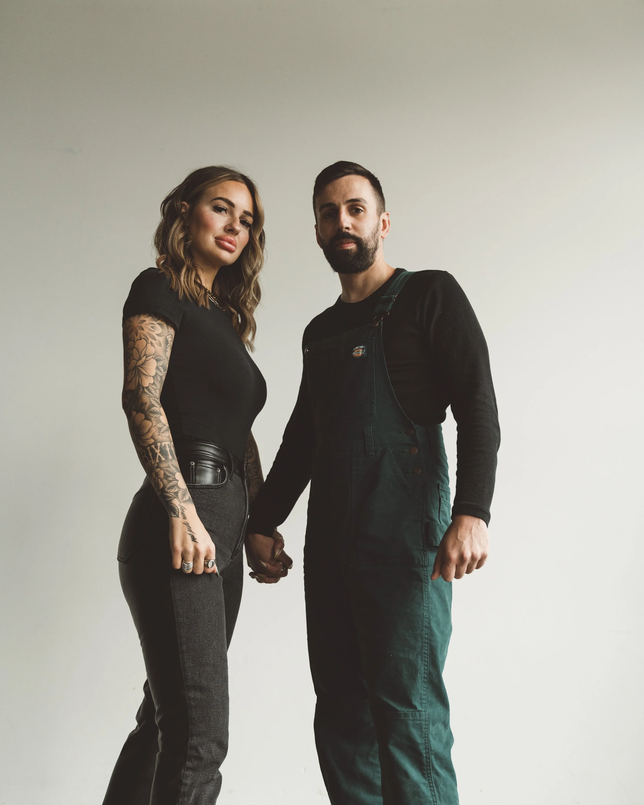 A man and woman holding hands against a plain white background.