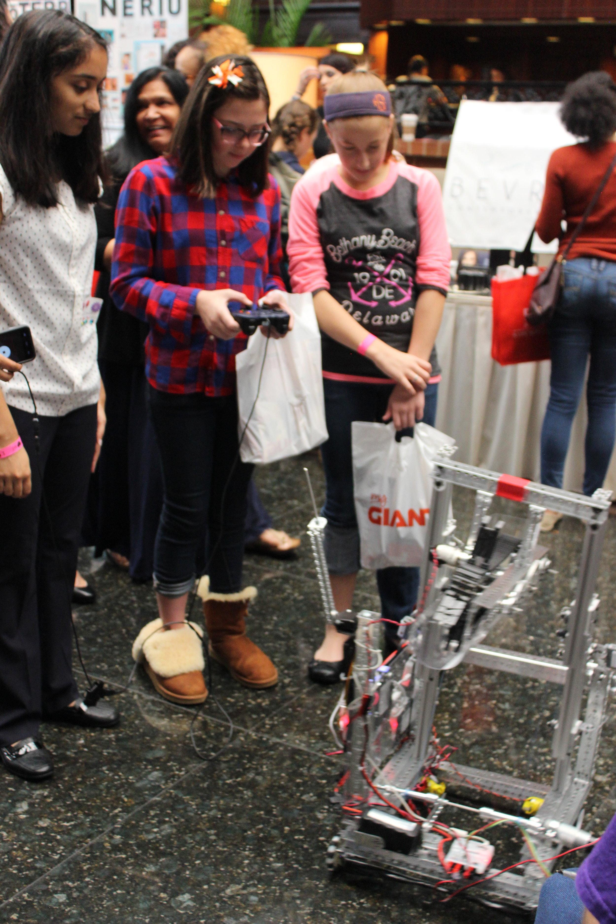  Rachael helps girls learn how to raise the robot's lift using the controllers. Girls World Expo, October 2016. 