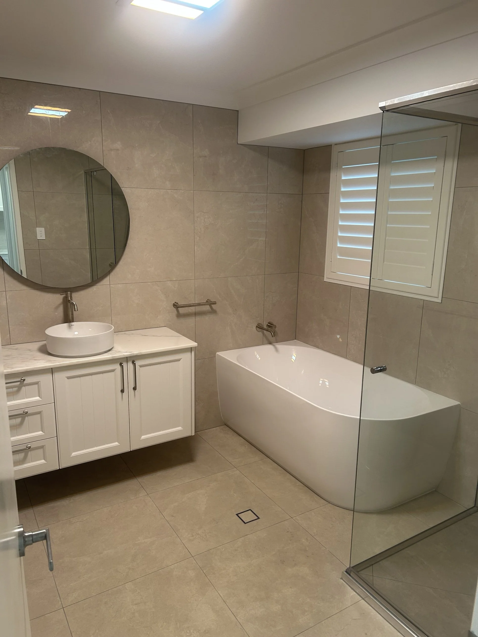 Finished bathroom renovation in Toowoomba with freestanding bath, wall-hung vanity, round mirror and large format tiles