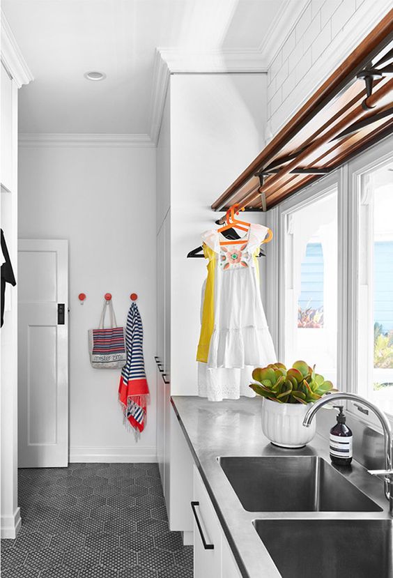 Shelf and rail all-in-one unit over a custom stainless steel bench with integrated sink. It’s certainly a laundry with high quality features. | Claire Stevens Interior Design