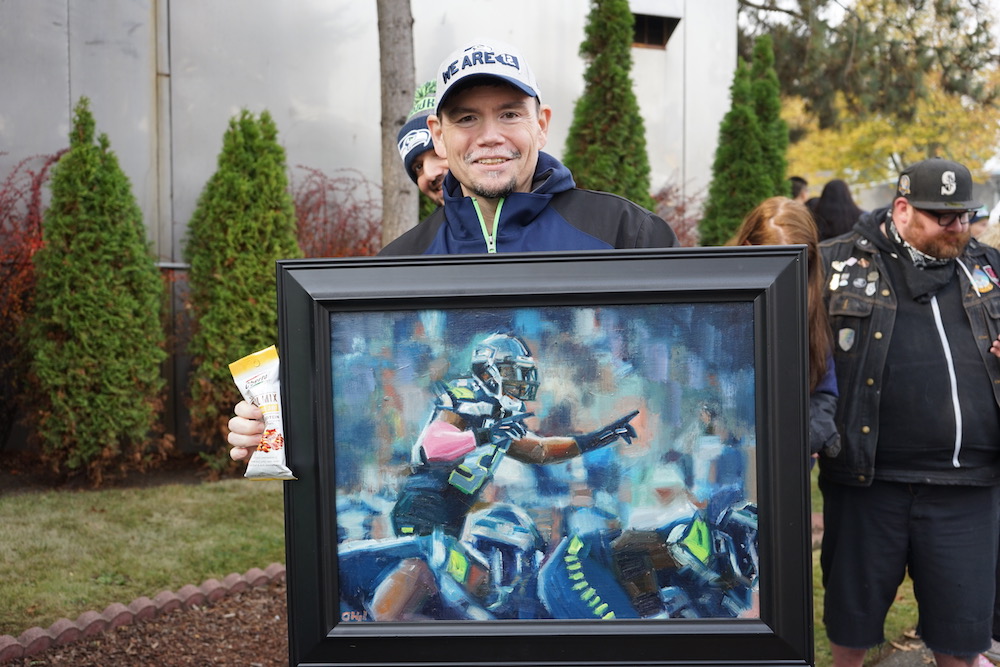 Fan holds a Bobby Wagner painting at the Oberto 100 year anniversary celebration with Bobby Wagner