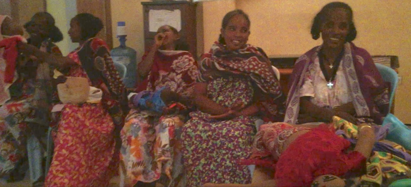Women who have recently been cured of obstetric fistula at the Healing Hands of Joy, examining Protect Your Sister Project's educational tools and having a good laugh.
