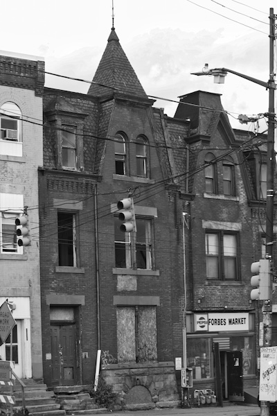 Johnny looked over his grandfather’s shoulder, out the window onto Dinwiddie Street, out over the buildings to the city. There were more and more darkened houses on the street, abandoned and dilapidated houses that, at one time, had been homes. Broken door- ways. Boarded-up windows. Broken glass in what little yellowed and burned grass survived the humidity of the dry summers in Pittsburgh. (Here Lies Memory, Black Scat Books)