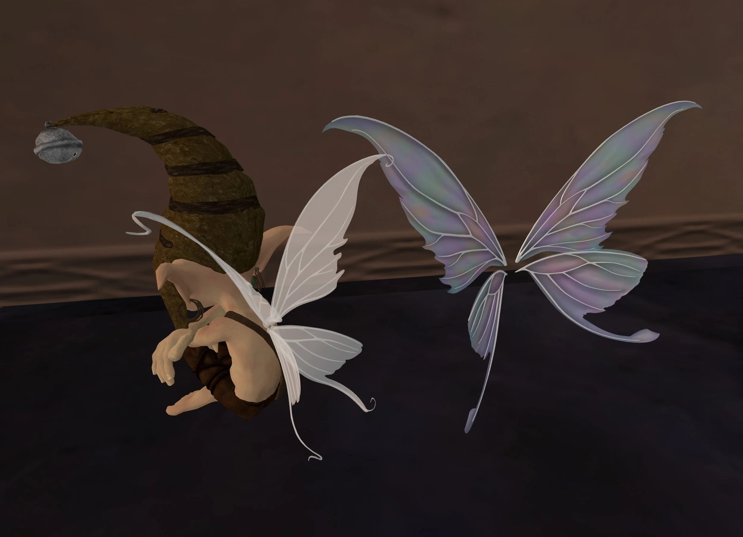 Photo from Second Life showing a sitting elf statue wearing sheer white fairy wings with white veins, pointed upper panels and lower panels with a tail, beside it are fairy wings of the same shape and design in pastel sheer buble colors.