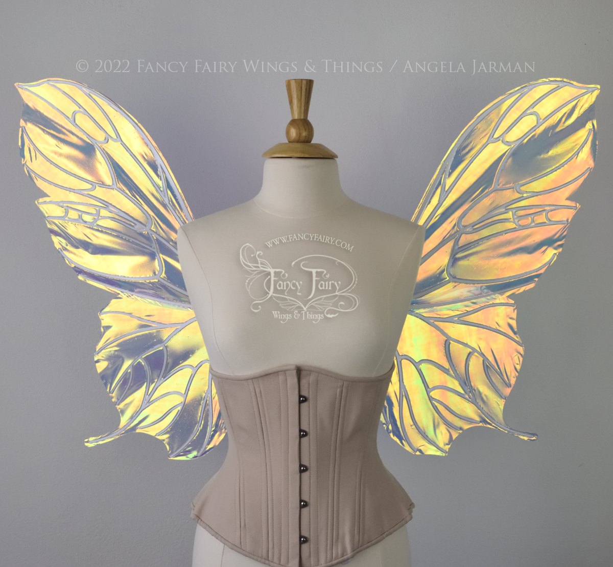  Front view of an ivory dress form wearing an alabaster underbust corset &amp; large iridescent fairy wings with a sort of butterfly shape. The veins are white 