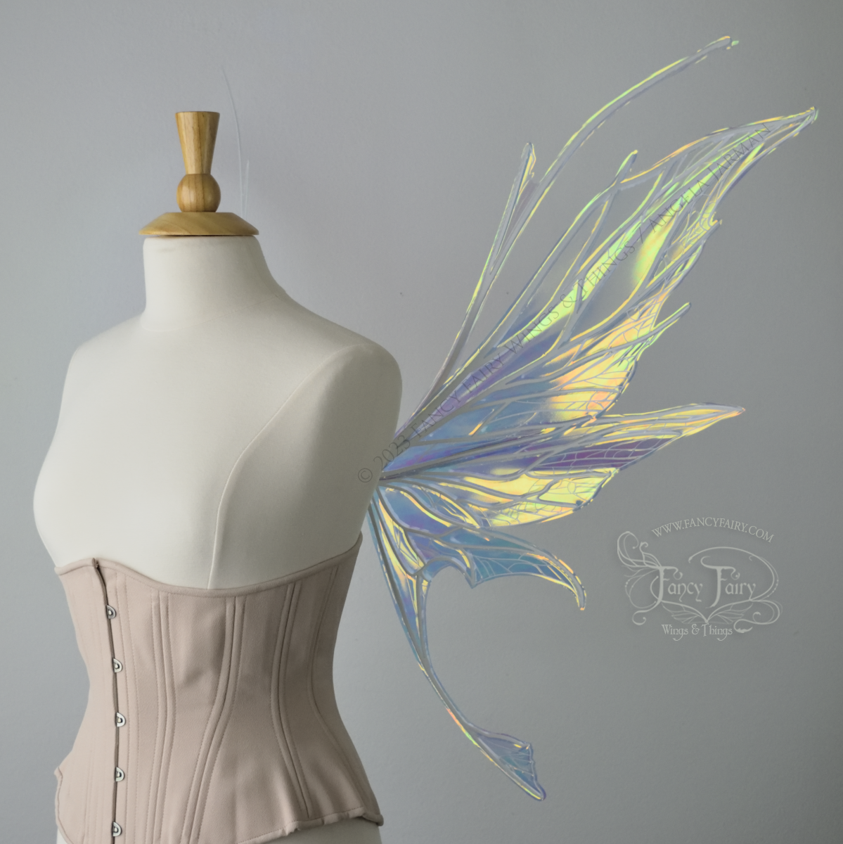  Right side view of an ivory dress form wearing an alabaster underbust corset and large multicolor iridescent fairy wings featuring antennae along the top. Upper panels come to a point as do the middle panels, bottom panels have tails. Spikey, detail