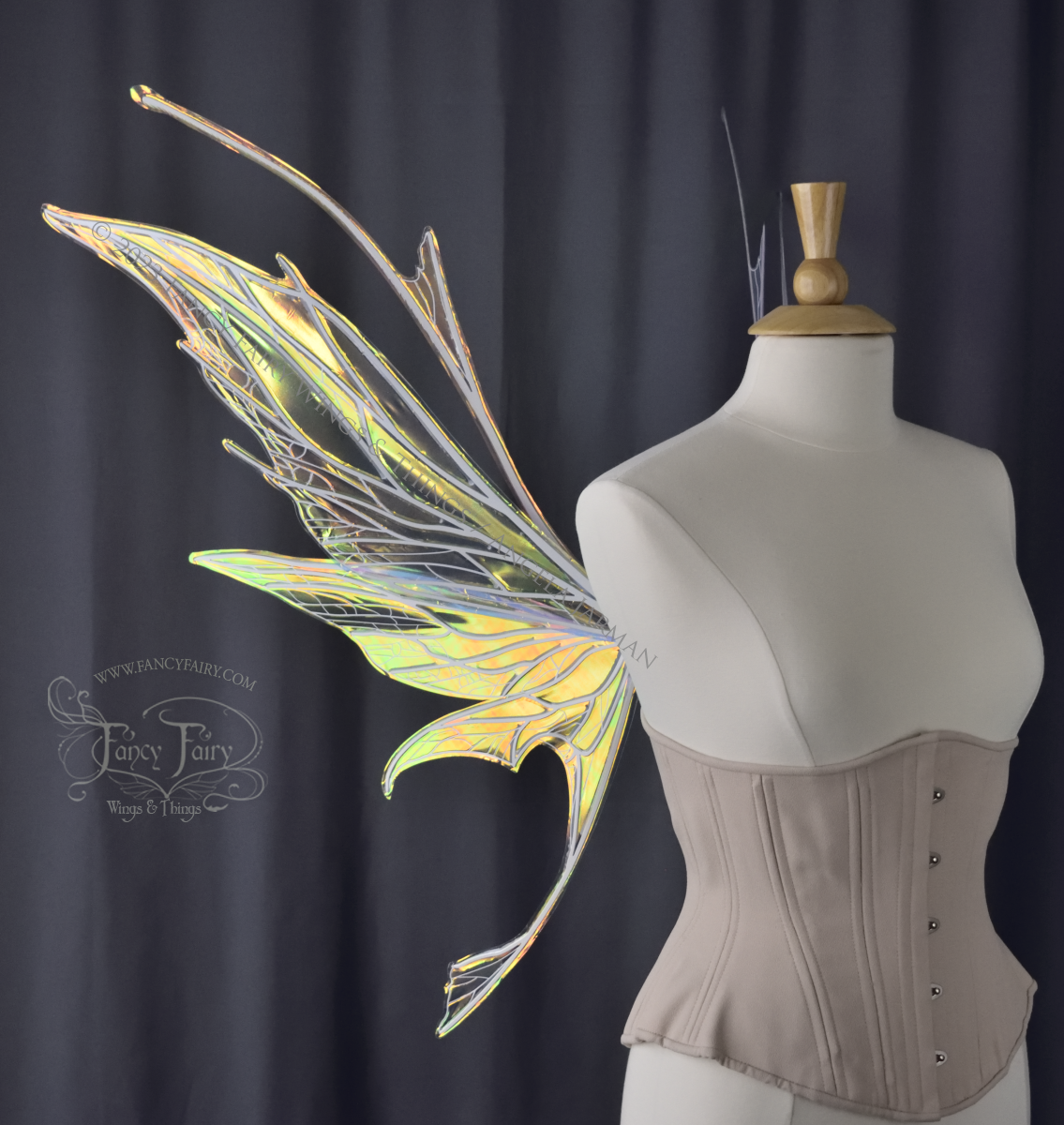  Left side view of an ivory dress form wearing an alabaster underbust corset and large multicolor iridescent fairy wings featuring antennae along the top. Upper panels come to a point as do the middle panels, bottom panels have tails. Spikey, detaile
