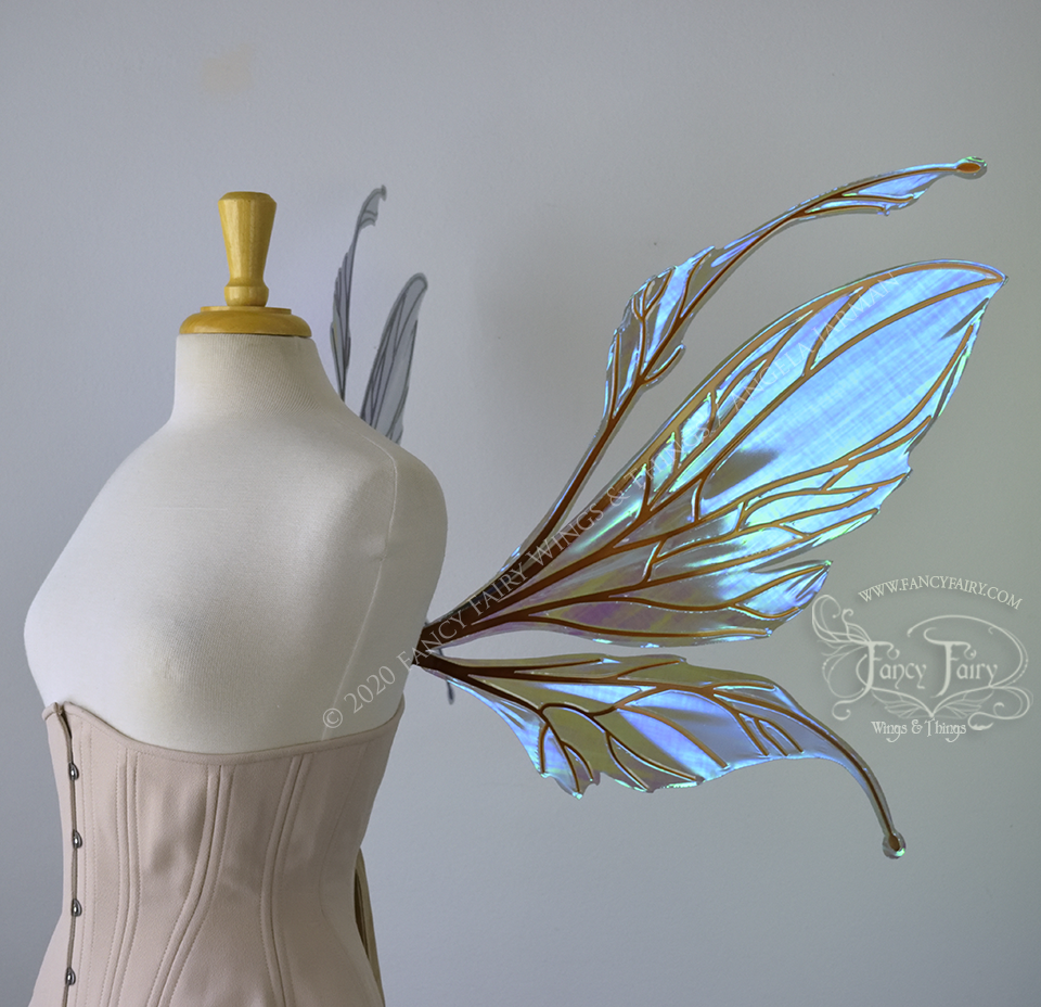  Right side view of an ivory dress form wearing an alabaster underbust corset and large iridescent purple / blue fairy wings featuring antennae along the top. The upper panels are elongated with semi-pointed tips, the lower panels are smaller with sl