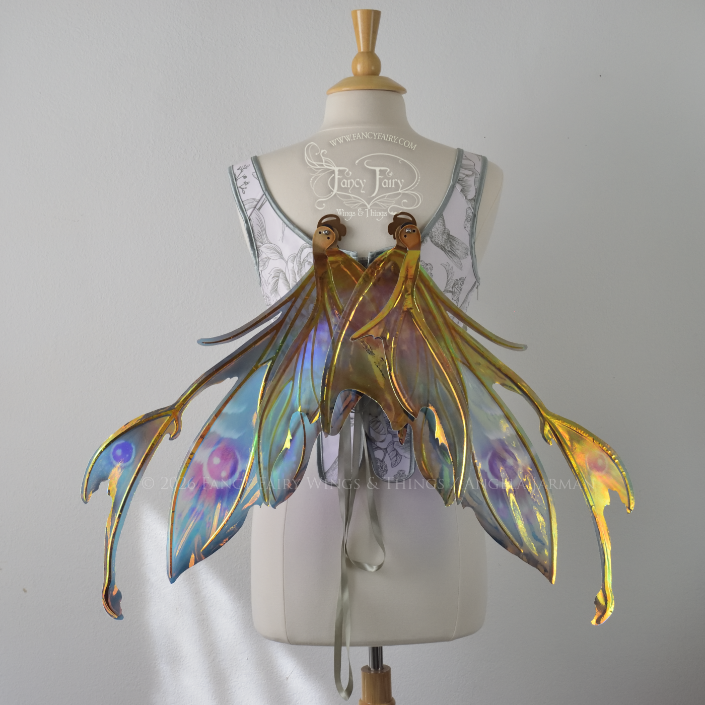  Iridescent fairy wings with a spikey profile &amp; antennae worn on a dress form, painted in shades of teal and purple, back view, in resting position 