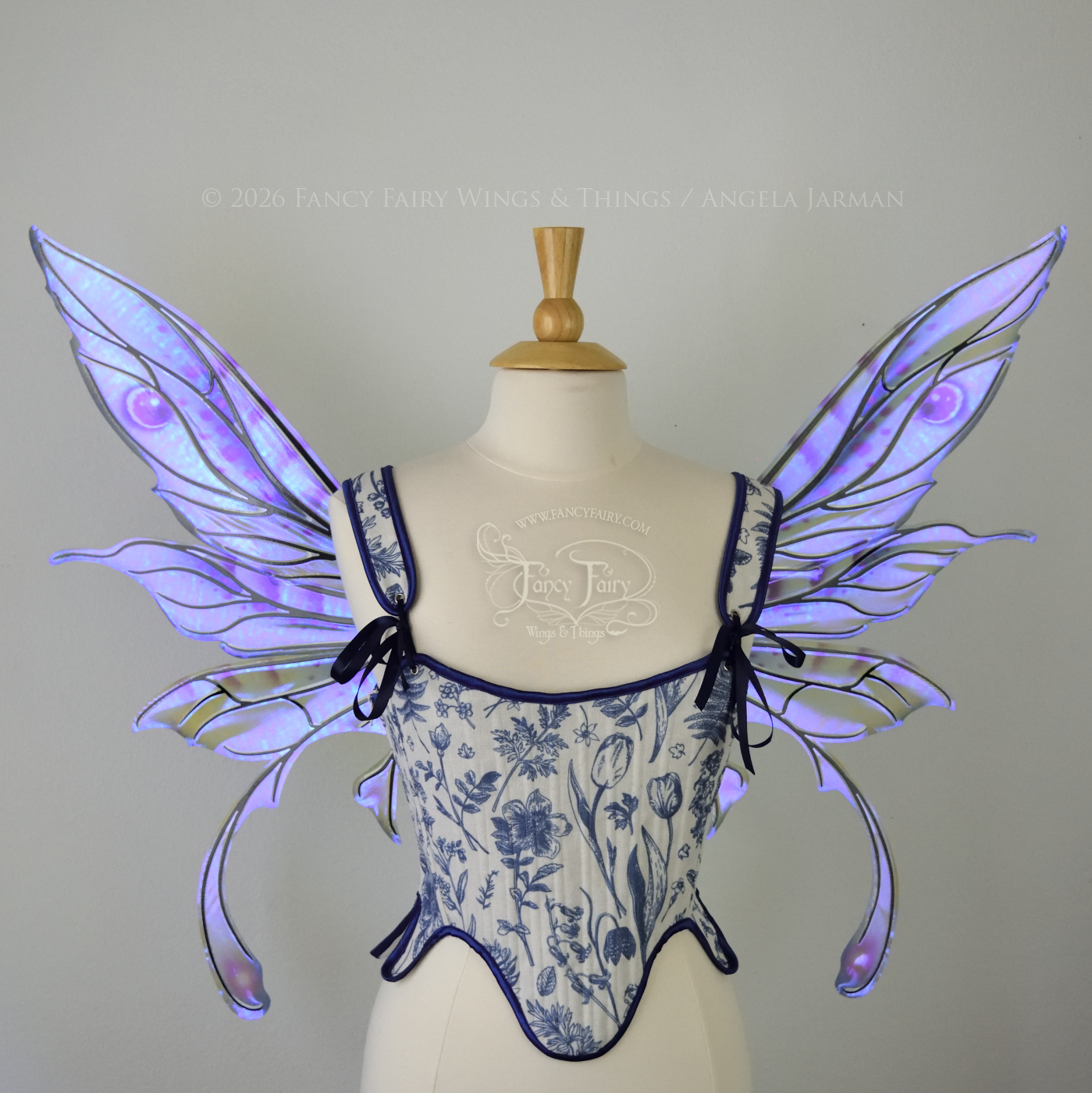 Transparent iridescent blue, fuchsia and violet fairy wings with black veins, 3 panels on each side, bottom panels have tails that curve inward at the bottom. Worn on a dress form, front view