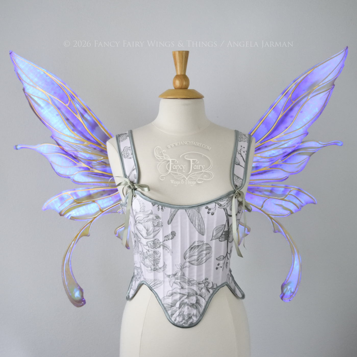 Transparent iridescent violet fairy wings with gold veins, 3 panels on each side, bottom panels have tails that curve inward at the bottom. Worn on a dress form, front view