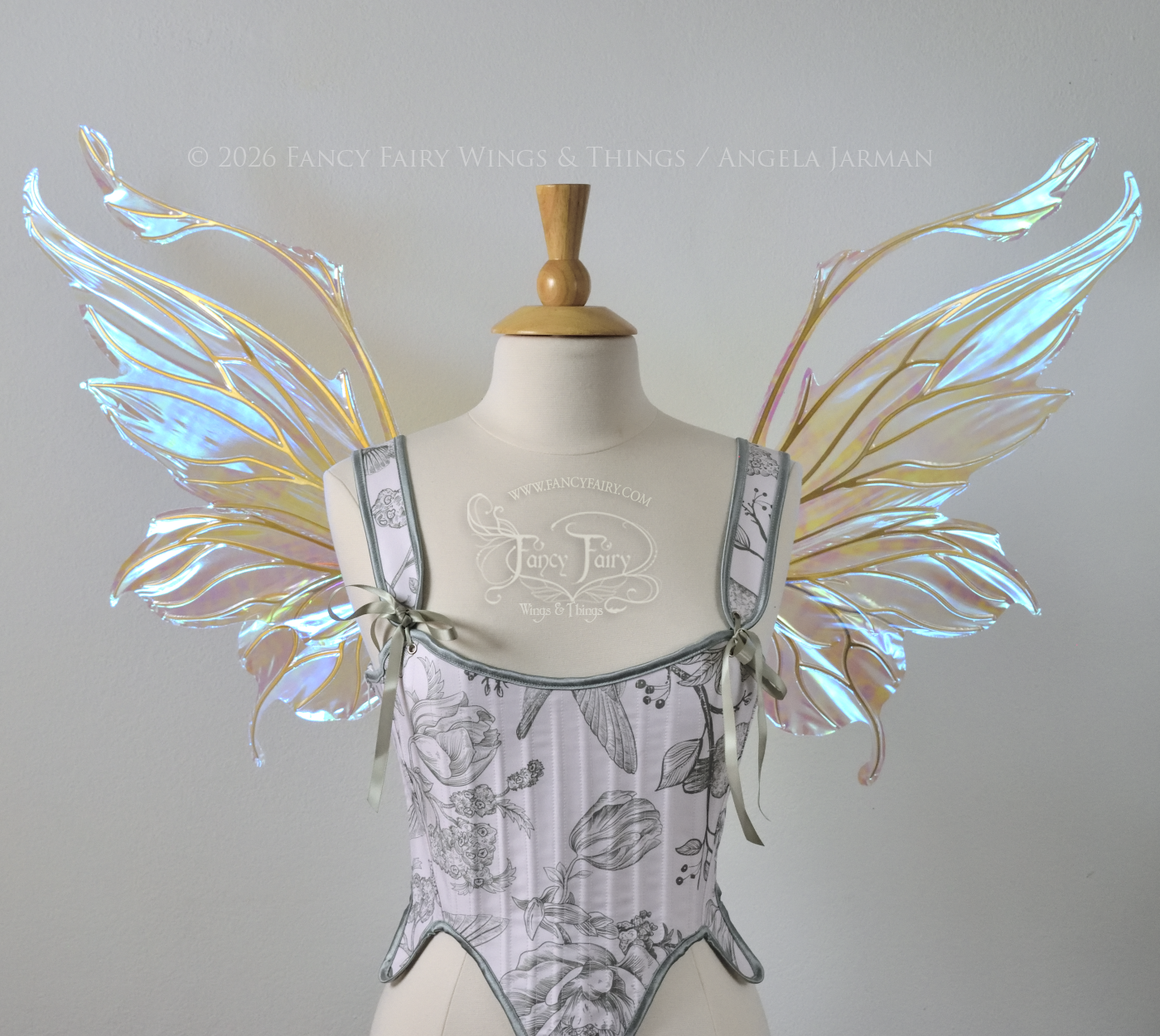 Transparent & iridescent fairy wings with blue shine and gold veins have antennae & upward curving tips, worn on a dress form, front view