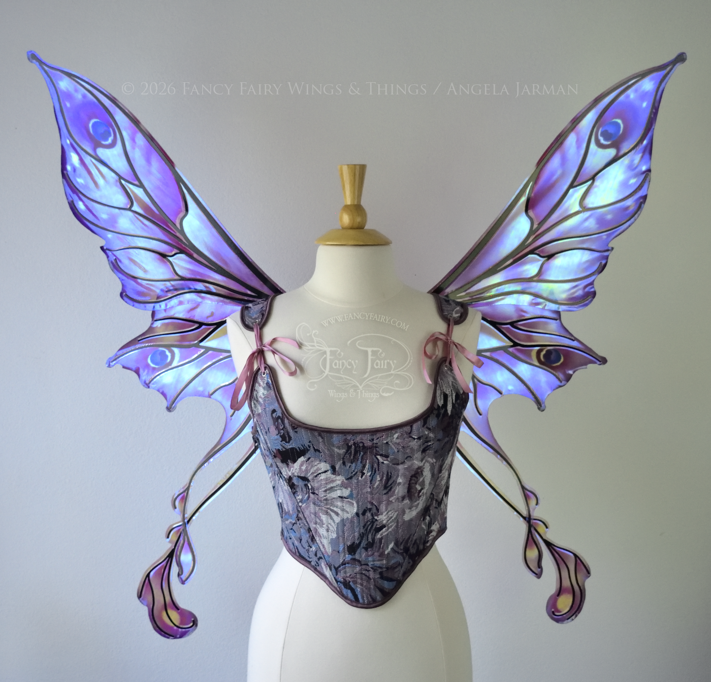 Iridescent & transparent fairy wings in shades of plum with a 'peacock' eye spot & black veins, features 2 swirling tails, worn on a dress form, front view