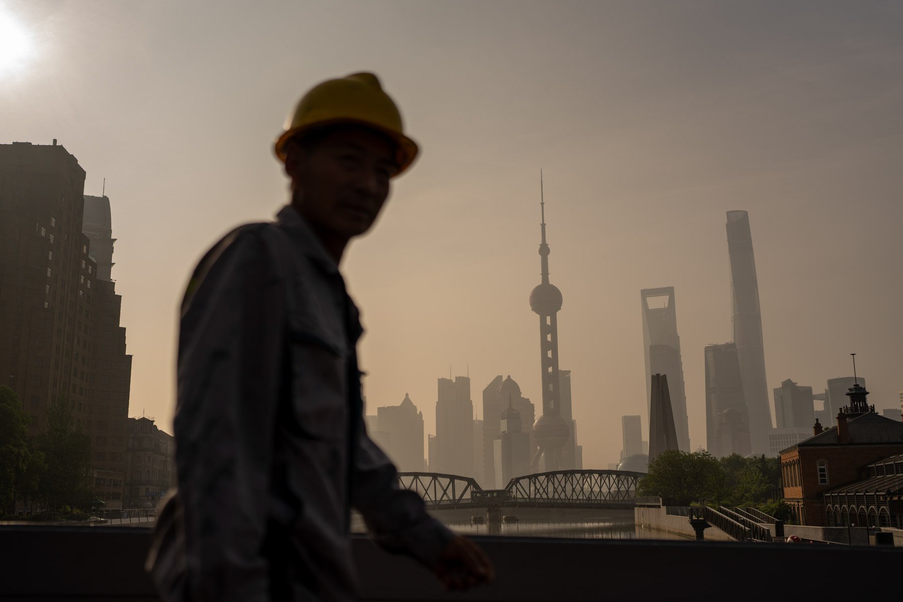  A worker walks along the Bund in front of buildings of the Lujiazui Financial District at sunrise in Shanghai, China on Wednesday, June 21, 2023. 