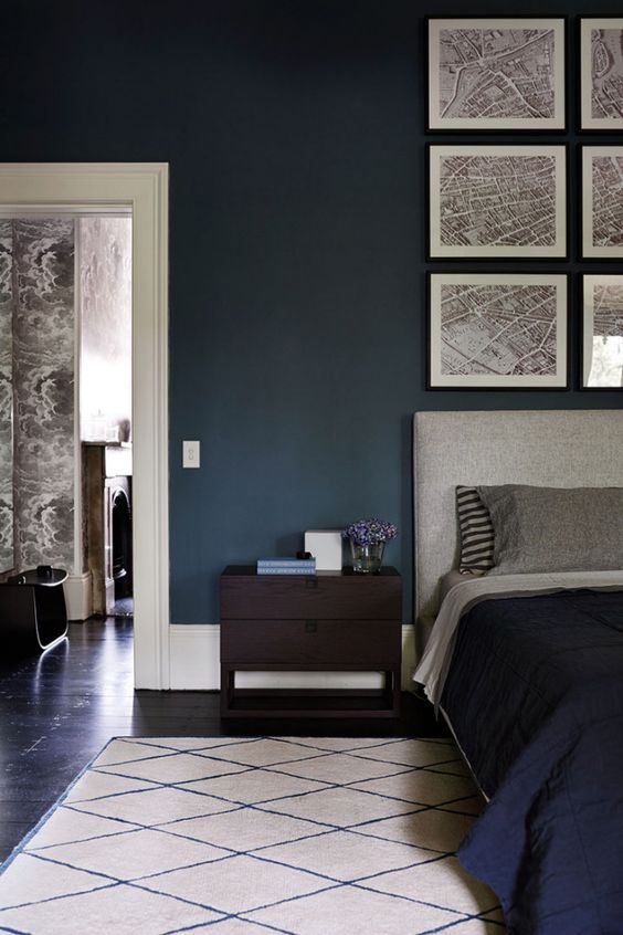 The rich wall colour gives this room depth and the display of maps above the headboard really stand out as a result. The dark floor and bedspread ground the wall colour, while the grey headboard, pillows and neutral rug unify the maps with the rest of the room.
