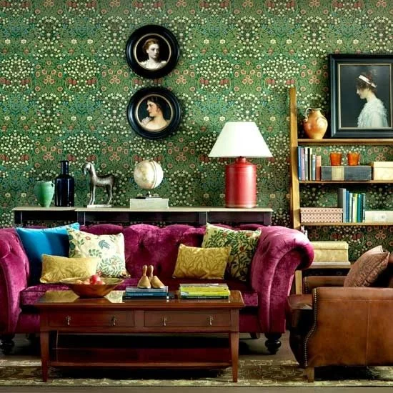 This room pays homage to Victorian styling. The patterned wallpaper and luxurious pink velvet sofa work really well. The patterned cushions unite the wallpaper and furnishings. The simple wall pictures and plain armchair and coffee table help to make this room feel comfortable and stop it from being over cluttered. 