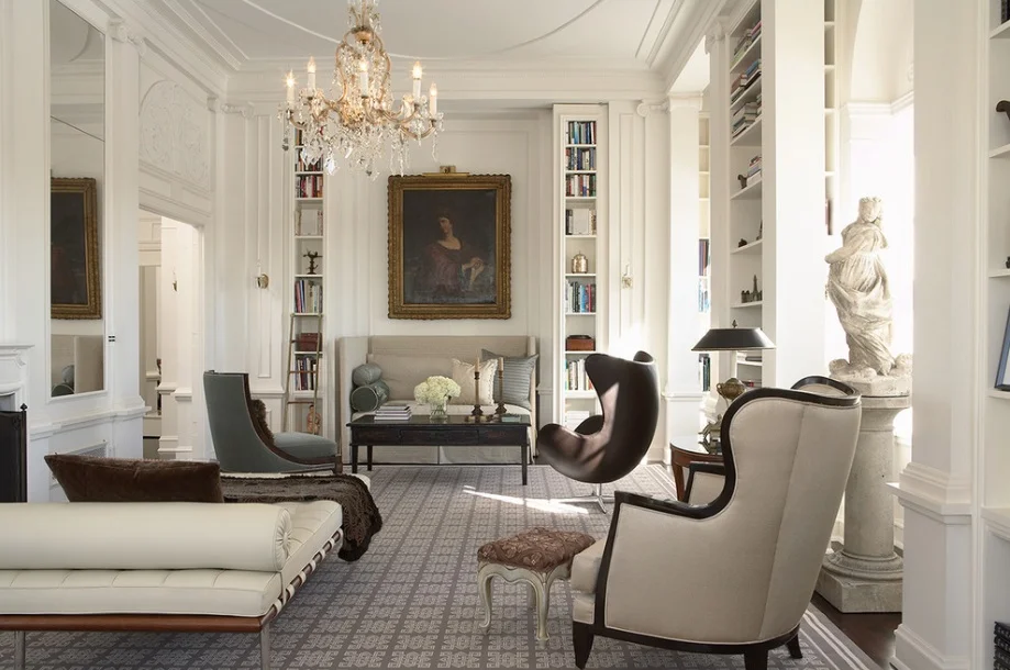This room beautifully merges classical and modern style. The white statue is prominent, but does not dominate and your eye is first drawn to the painting at the end of the room, as well as the chandelier at the top. This allows the looker to appreciate the size and height of the room. The coffee table, as well as the wood of the furniture is dark, which would be in keeping with Victorian tastes. The light walls provide a perfect backdrop to help the furniture and accessories stand out in their creams and muted shades. The overall effect is well balanced and comfortable. 