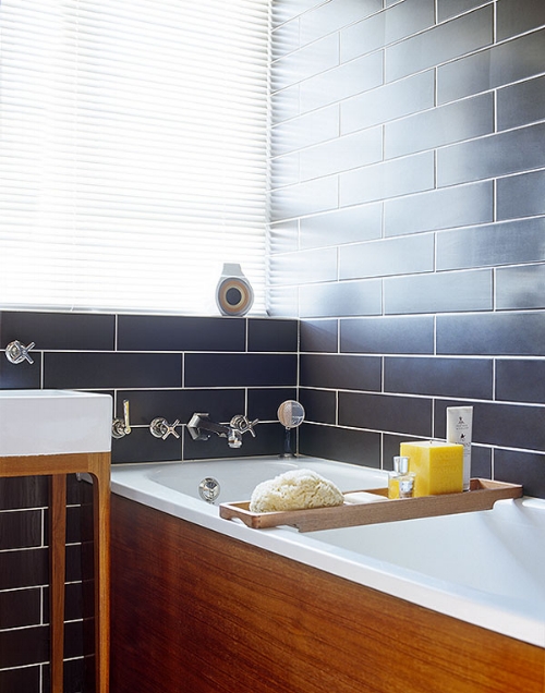 Rich teak encases the bath and provides support for the sink. This contrasts well with the dark brickwork. Image: designhunter.co.uk