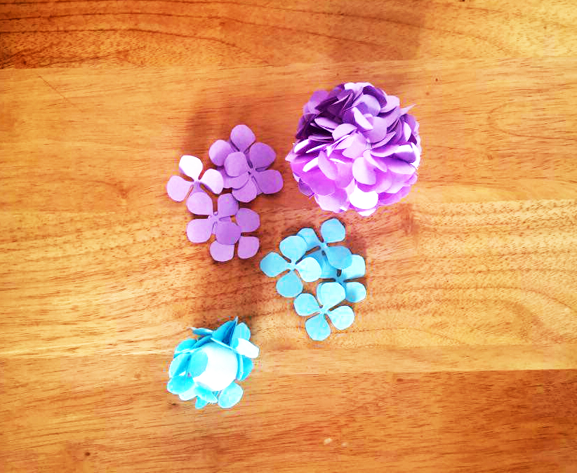 Paso 3 - Con cuidado con la pega caliente, pega en las bolas los petalos cercas unos de los otros para que queden hacia arriba. Continúa hasta que forres la bola completa. // Carefully with the glue gun, glue on the balls the petals close to each other so that they lift up. Keep going until ou have covered the ball.