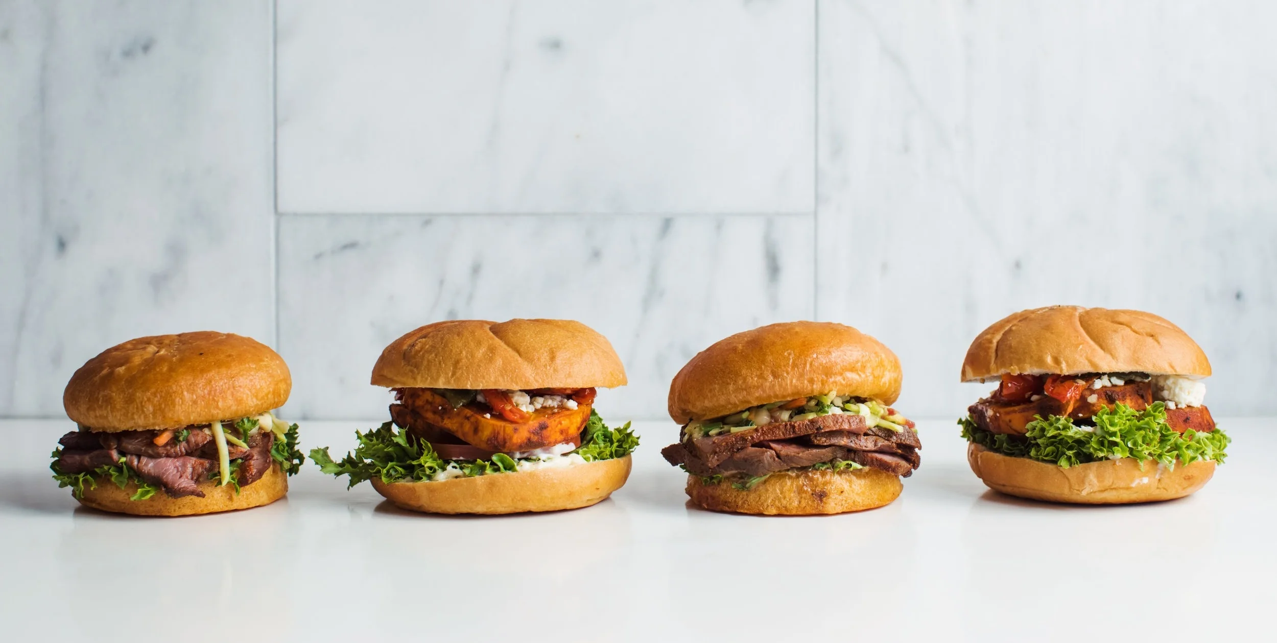 Four sandwiches on marble from QC Direct drop-off catering.jpg