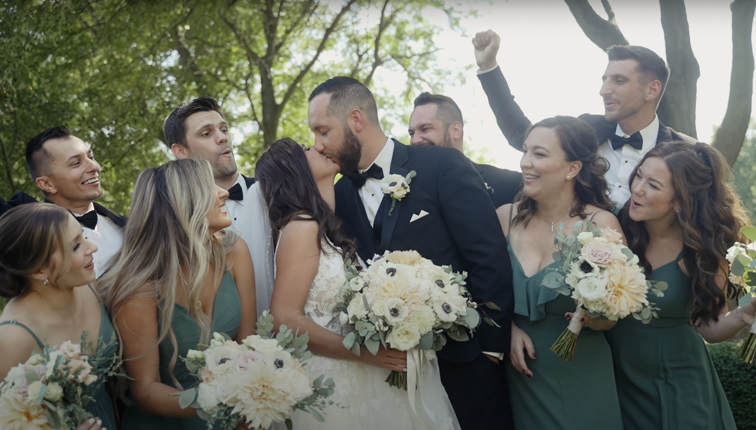wedding couple kiss while bridal party cheers